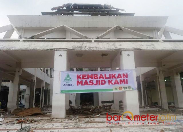 KEMBALIKAN MASJID KAMI: Pengurus GP Ansor Surabaya membentangkan spanduk di lokasi pembongkaran agar bangunan masjid dikembalikan seperti semula. | Foto: Barometerjatim.com/ROY HASIBUAN