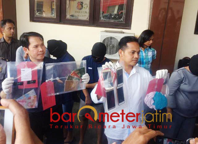 BARANG BUKTI: Petugas menunjukkan barang bukti dari penggerebekan seks tukar pasangan. | Foto: Barometerjatim.com/NATHA LINTANG