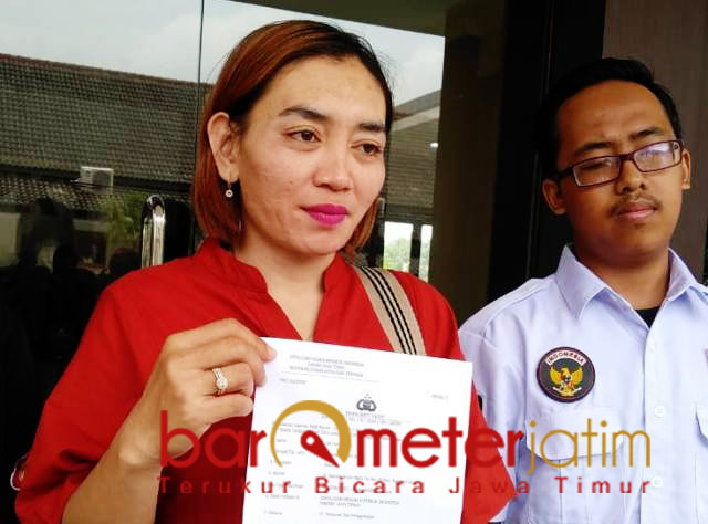 Sri Wahyuni menunjukkan laporannya ke Polda Jatim atas dugaan penipuan. | Foto: Barometerjatim.com/natha lintang