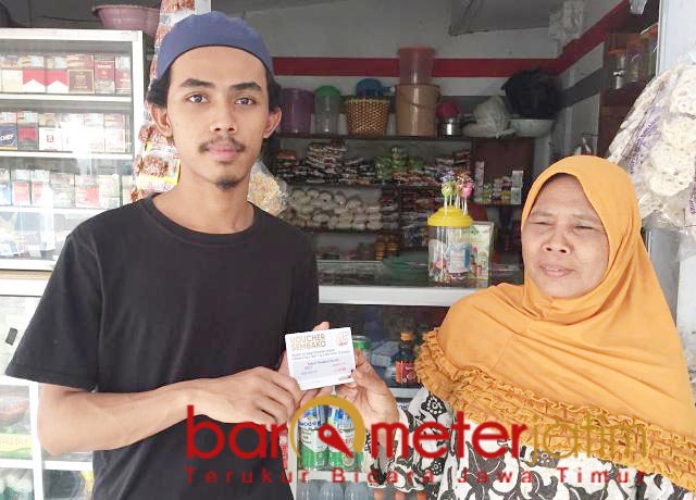 VOUCHER SEMBAKO: Seorang ibu menukarkan voucher sembako bantuan Anwar Sadad di warung. | Foto: Barometerjatim.com/ROY HS