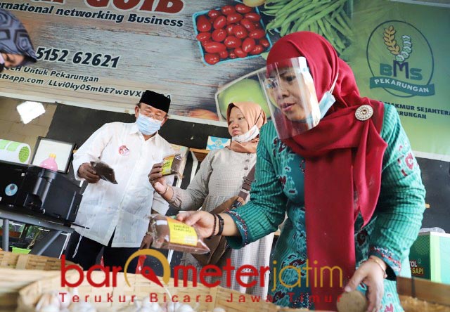 SERBA ADA: Dwi Astutik mencermati salah satu produk jamu di Pasar Goib Desa Pekarungan, Sukodono. | Foto: Barometerjatim.com/ROY HS