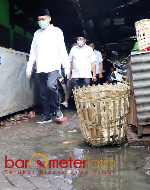 MASIH BECEK: Kelana dan Haji Masnuh melewati sudut pasar yang sedikit becek akibat hujan. | Foto: Barometerjatim.com/ROY HS