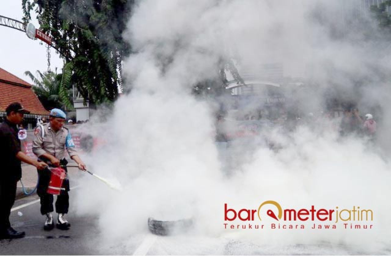 PADAMKAN API: Petugas kepolisian memadamkan api dari ban yang dibakar demonstran. | Foto: Barometerjatim.com/RQ