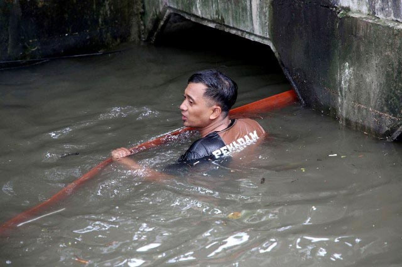 ATASI BANJIR: Petugas turun ke sungai memastikan aliran air tak ada hambatan. | Foto: Barometerjatim.com/HPS