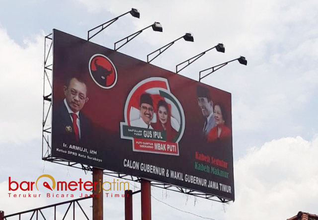 BELUM DITURUNKAN: Meski menyalahi aturan pemasangan APK, billboard paslon ini masih berdiri kokoh dan tak kunjung diturunkan Bawaslu. | Foto: Barometerjatim.com/ABDILLAH HR