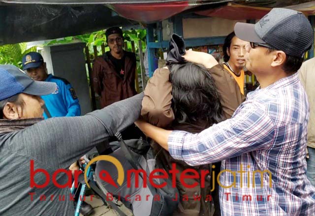 Petugas berpakaian preman menangkap salah seorang berjaket hoodie. | Foto: Barometerjatim.com/nantha lintang