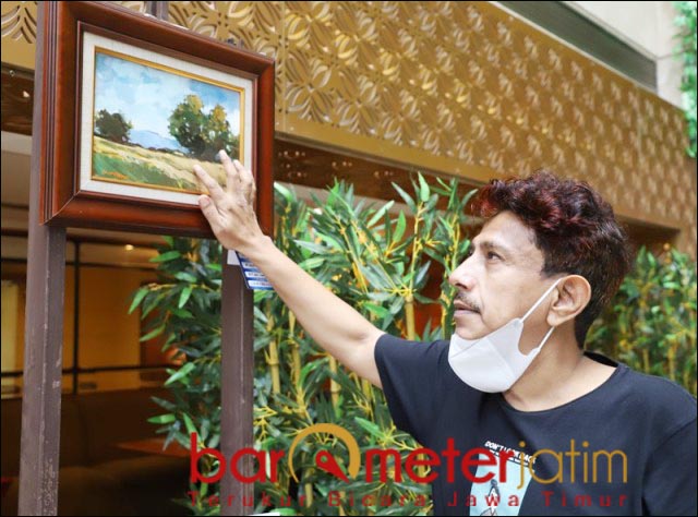 TOKOH IMPRESIONIS: Hamid Nabhan dan lukisan impresionis karyanya yang dipajang dalam pemeran. | Foto: Barometerjatim.com/ROY HS