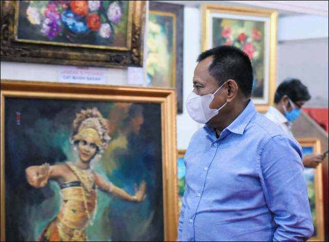 EKSPRESI: Heru Tjahjono, melihat lukisan di Pasar Seni Lukis Indonesia (PSLI) 2021. | Foto: Barometerjatim.com/IST