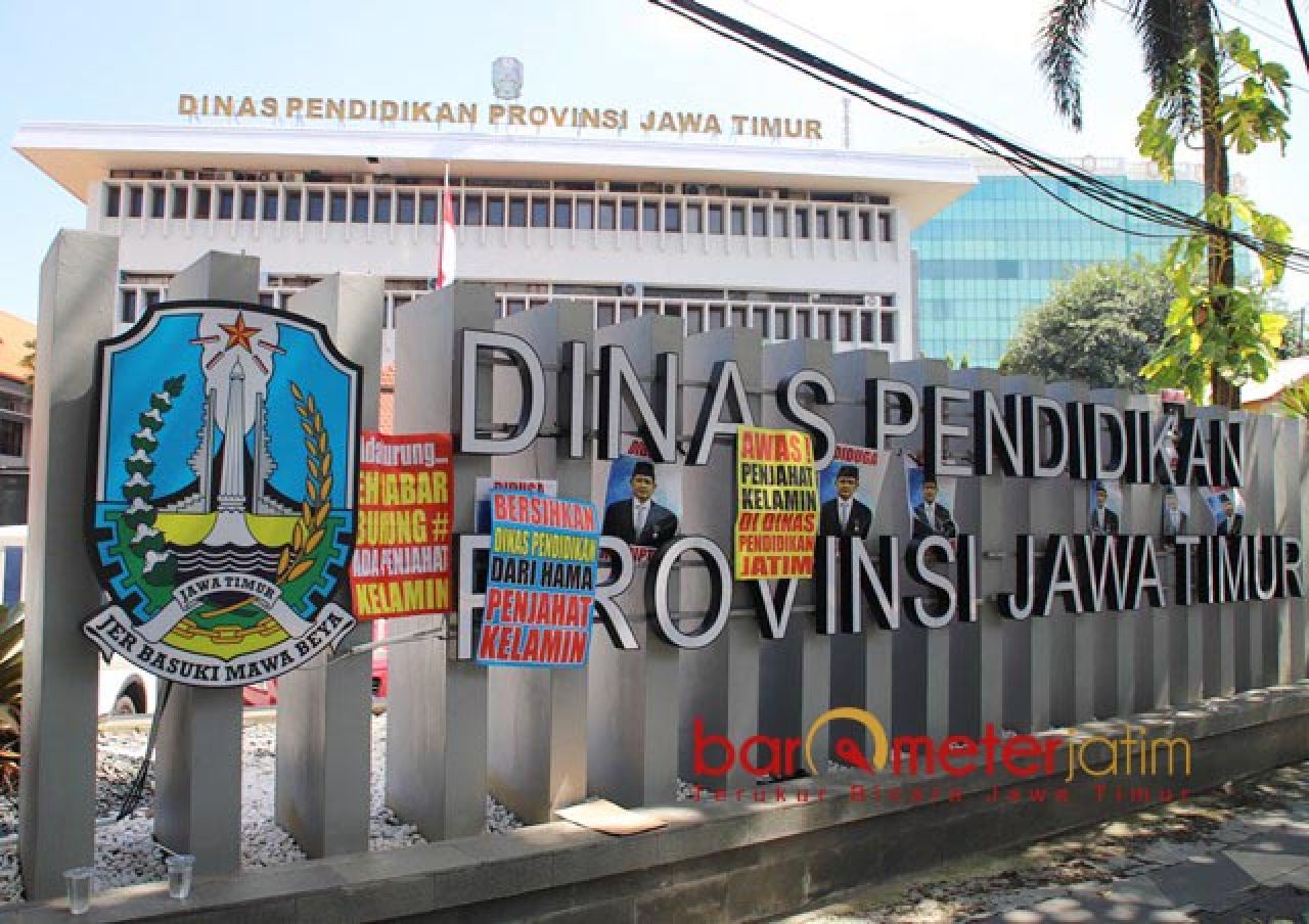 SIMBOL PROTES: Massa GAM Jatim menempelkan poster di pagar gedung Dindik Jatim. | Foto: Barometerjatim.com/BKT